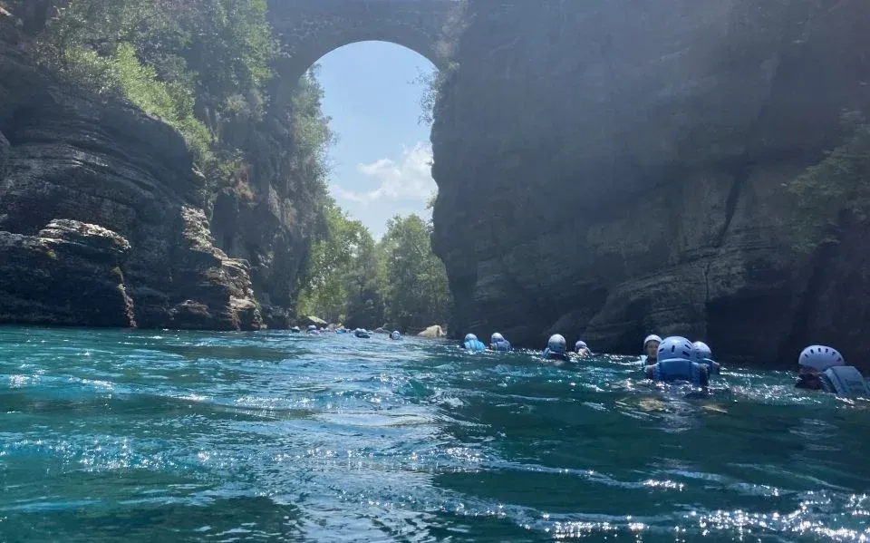 Die römische Oluk-Brücke hoch über dem türkisfarbenen Köprüçay, darunter Rafter mit Helmen in der Strömung