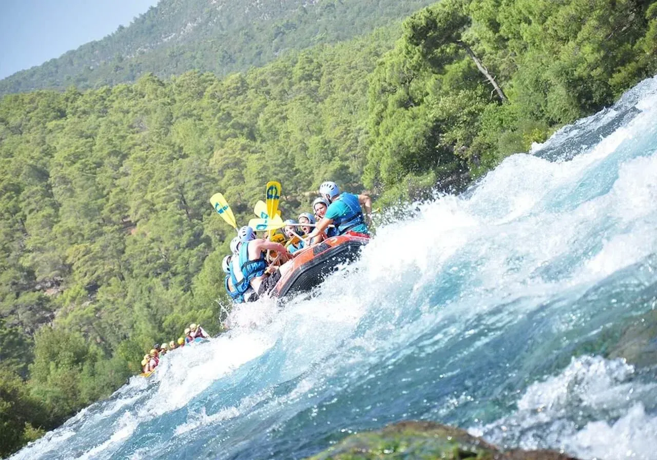Rafter auf einer Welle aus Gischt im Köprüçay unterhalb bewaldeter Hänge